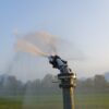 A water sprinkler system can be seen sprinkling water in a green field