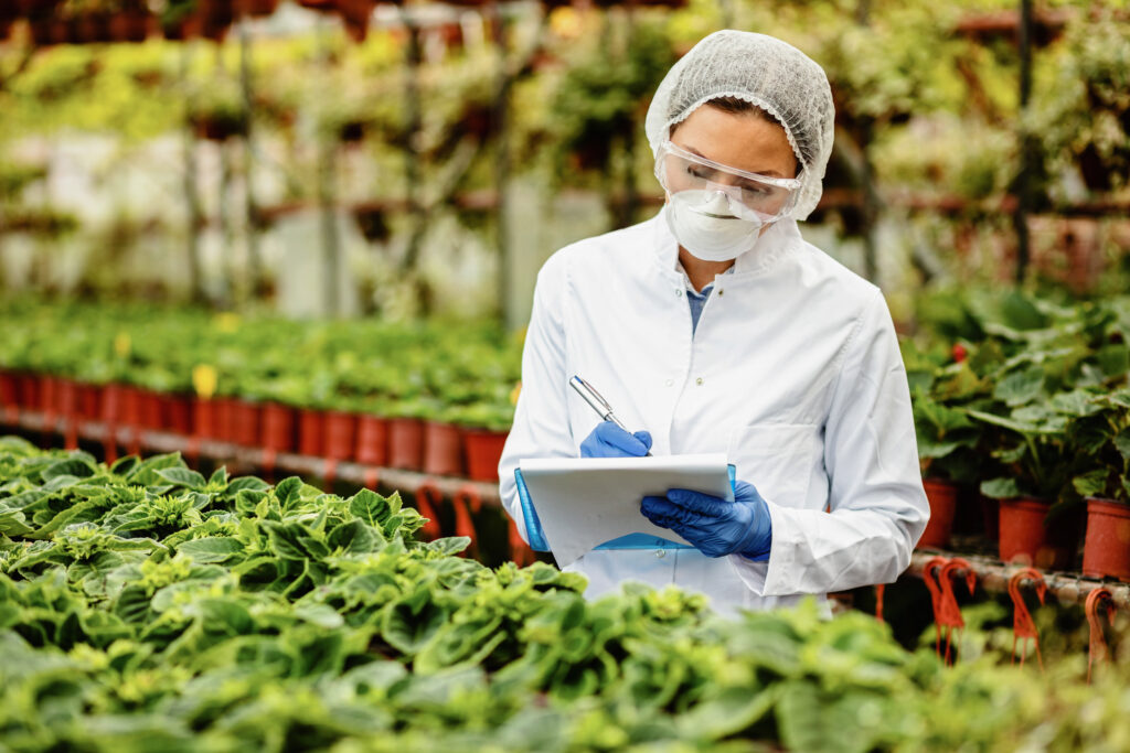 A woman scientist can be seen inspecting the plants and taking notes in her diary, she's covered in an all white uniform with a head cover